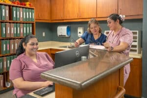 Three nurses at a front desk together
