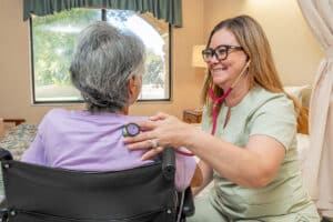 A nurse taking an elderly woman's heartbeat