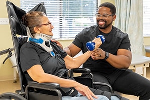 A physical therapist helping a woman lift a dumbbell